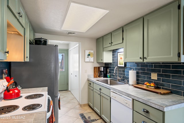 kitchen with backsplash, white appliances, sink, green cabinets, and light tile patterned flooring