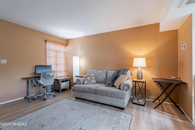 home office featuring light hardwood / wood-style floors and brick wall