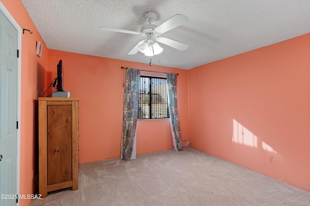 carpeted spare room featuring ceiling fan and a textured ceiling