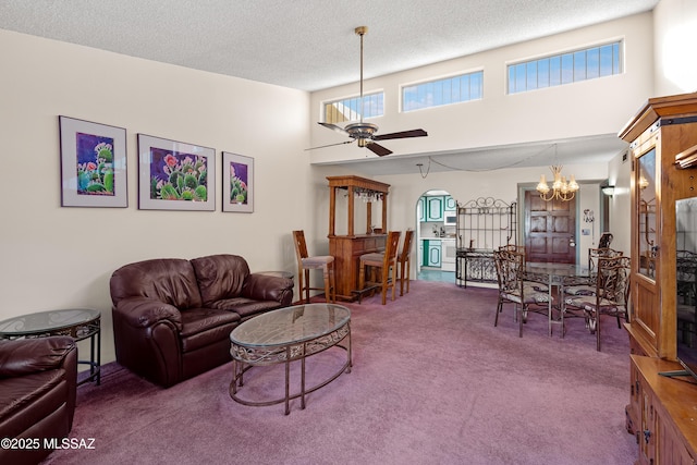 living room featuring ceiling fan with notable chandelier, carpet floors, a textured ceiling, and a towering ceiling