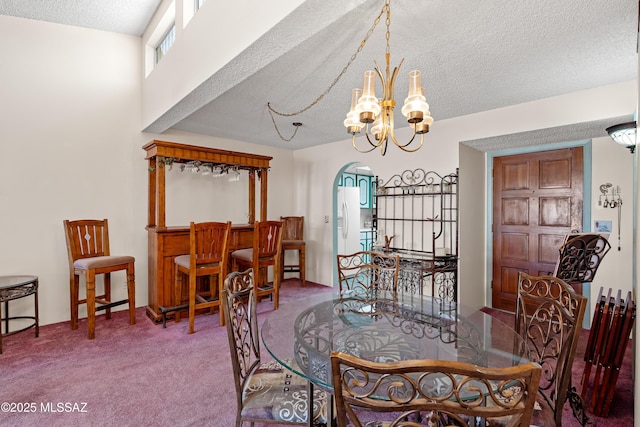 carpeted dining space with a notable chandelier and a textured ceiling