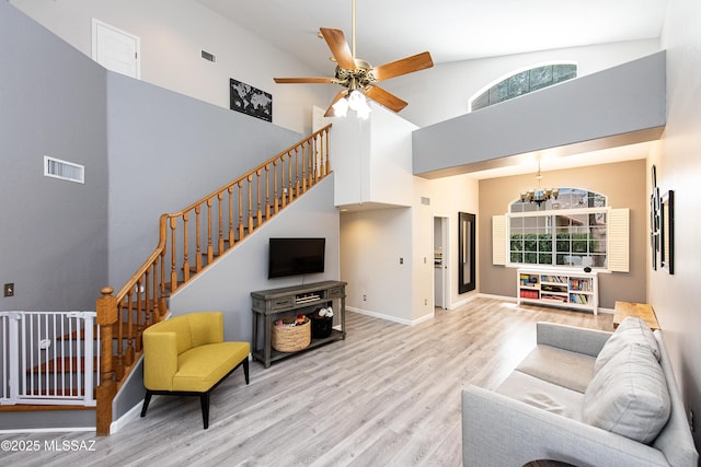 living room with a healthy amount of sunlight, light hardwood / wood-style floors, high vaulted ceiling, and ceiling fan with notable chandelier