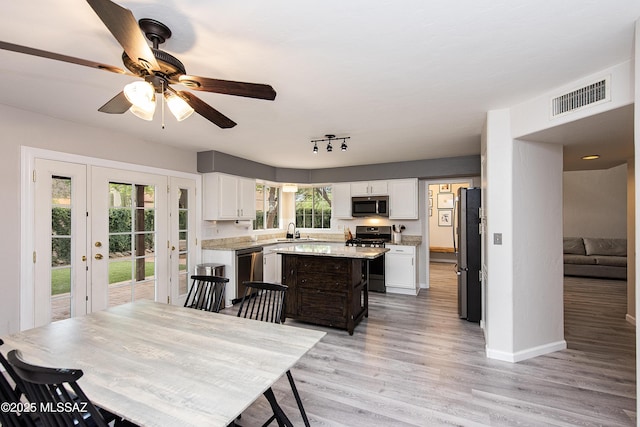 kitchen featuring white cabinets, light hardwood / wood-style floors, stainless steel appliances, a kitchen island, and sink