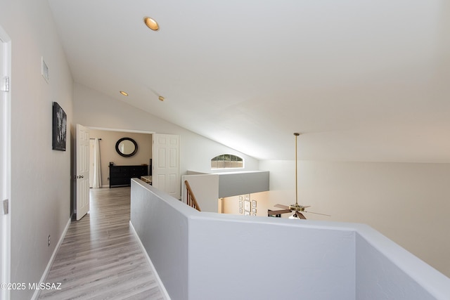 corridor with light hardwood / wood-style flooring and lofted ceiling