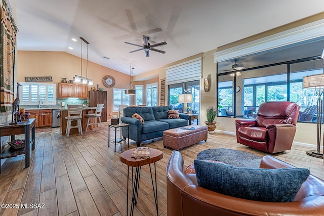 living room with lofted ceiling, ceiling fan, a wealth of natural light, and sink