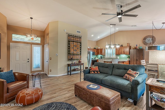 living room with light hardwood / wood-style floors, vaulted ceiling, and ceiling fan with notable chandelier