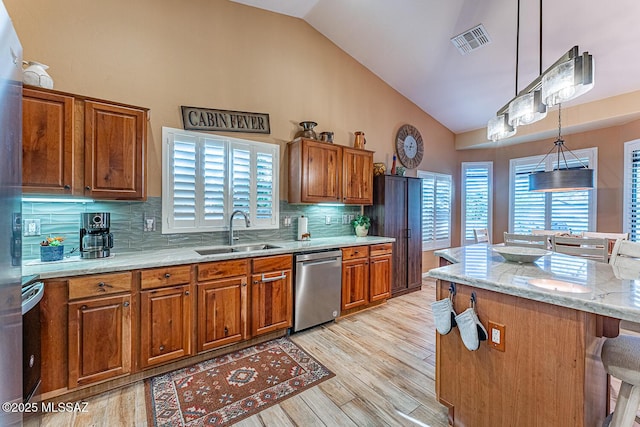 kitchen featuring stainless steel dishwasher, a center island, hanging light fixtures, tasteful backsplash, and sink