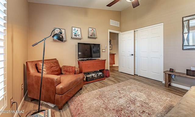 living room with light hardwood / wood-style floors, ceiling fan, and vaulted ceiling