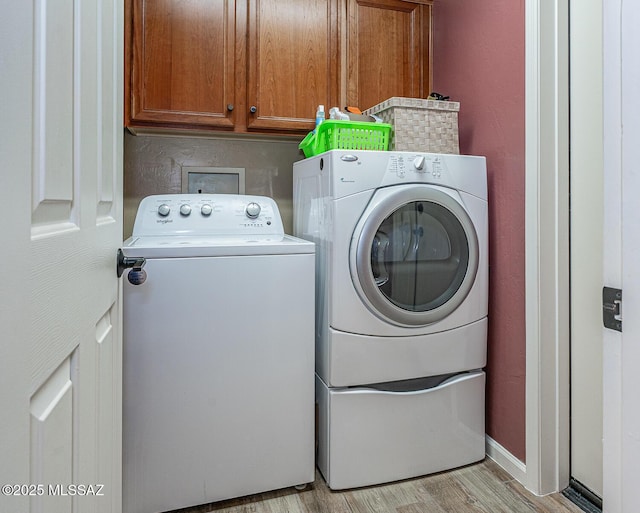 washroom with cabinets, washing machine and dryer, and light wood-type flooring