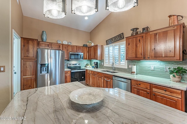 kitchen featuring vaulted ceiling, appliances with stainless steel finishes, hanging light fixtures, decorative backsplash, and sink