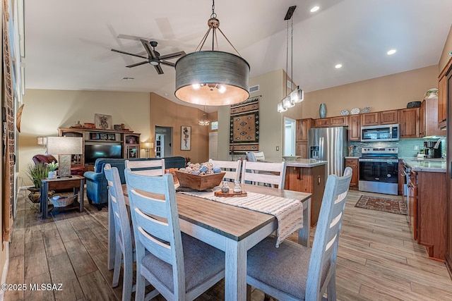 dining room featuring ceiling fan, vaulted ceiling, and light hardwood / wood-style floors