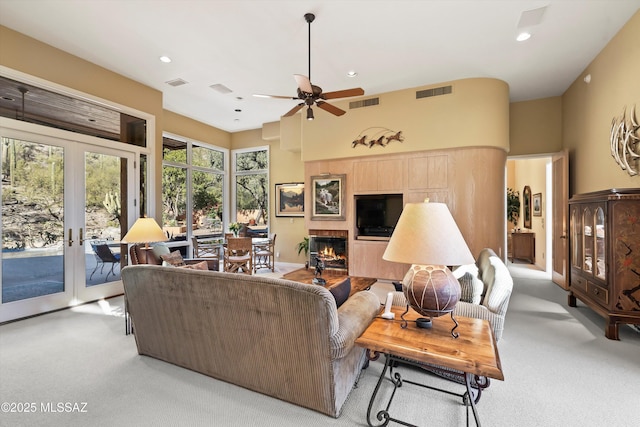 carpeted living room featuring a tile fireplace, french doors, and ceiling fan