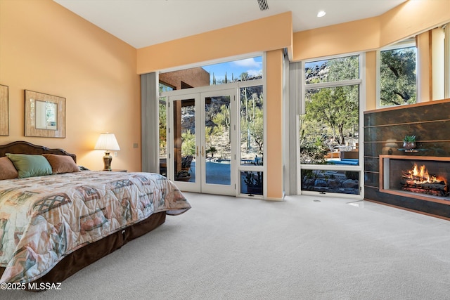 carpeted bedroom featuring a tile fireplace, access to outside, and french doors