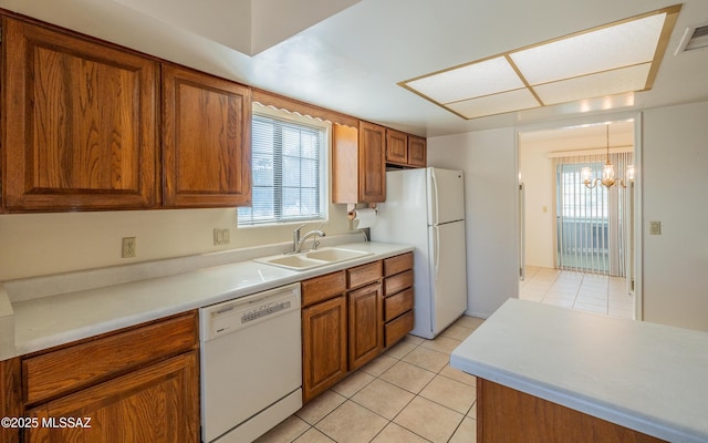 kitchen featuring white appliances, sink, a wealth of natural light, and an inviting chandelier