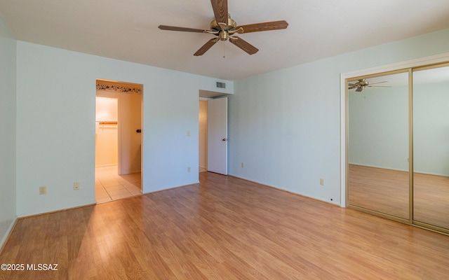 unfurnished bedroom featuring ceiling fan, a closet, and light hardwood / wood-style floors