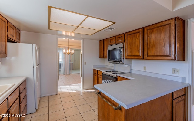 kitchen featuring a notable chandelier, white appliances, kitchen peninsula, and light tile patterned floors