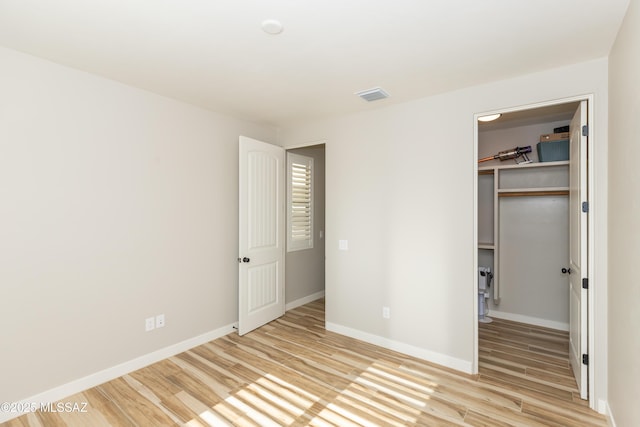 unfurnished bedroom with a walk in closet, light hardwood / wood-style flooring, and a closet