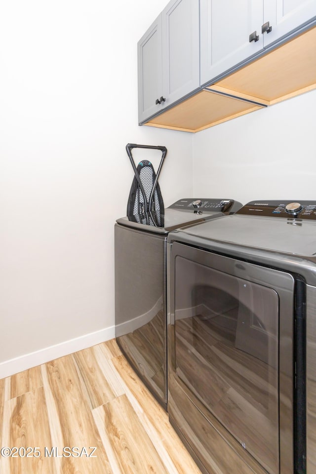 washroom featuring washer and dryer, light hardwood / wood-style floors, and cabinets