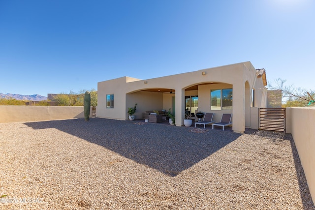 back of house featuring ceiling fan, a mountain view, and a patio