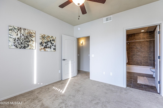 unfurnished bedroom featuring a spacious closet, ensuite bathroom, ceiling fan, and carpet floors