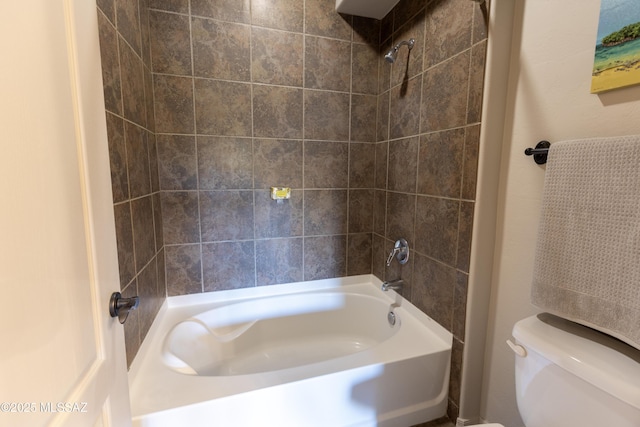 bathroom featuring tiled shower / bath combo and toilet