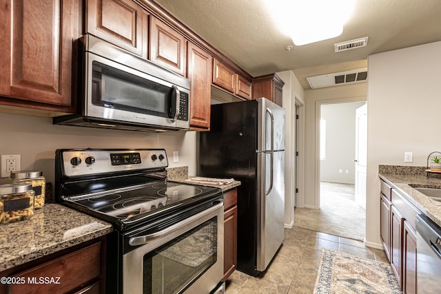 kitchen with sink, stone countertops, light colored carpet, and stainless steel appliances