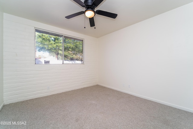 unfurnished room featuring ceiling fan, brick wall, and carpet floors