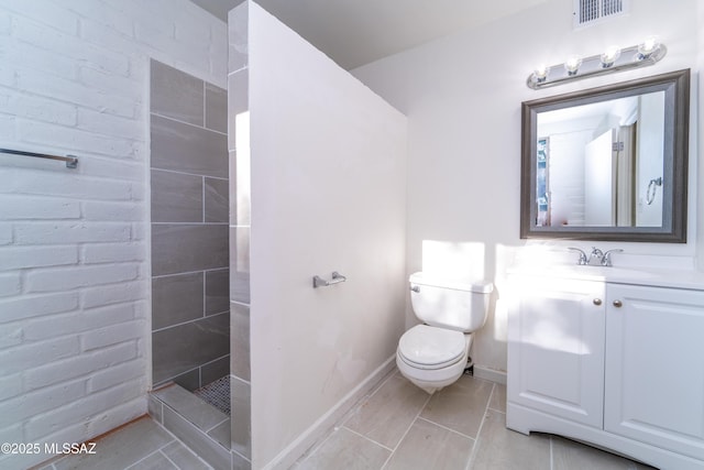 bathroom with a tile shower, vanity, and toilet