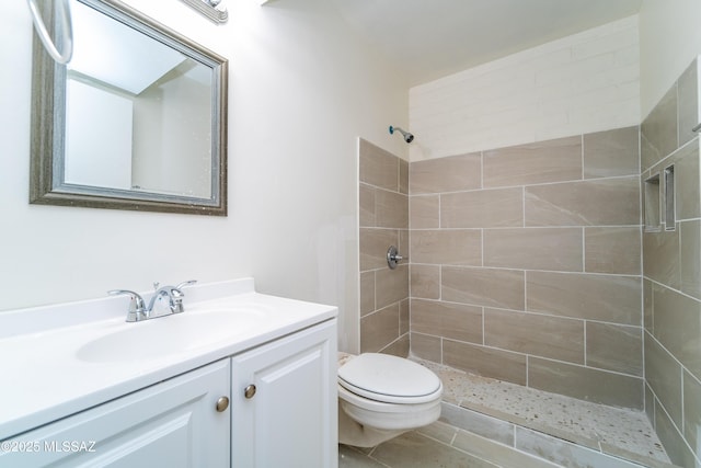 bathroom with vanity, toilet, and a tile shower