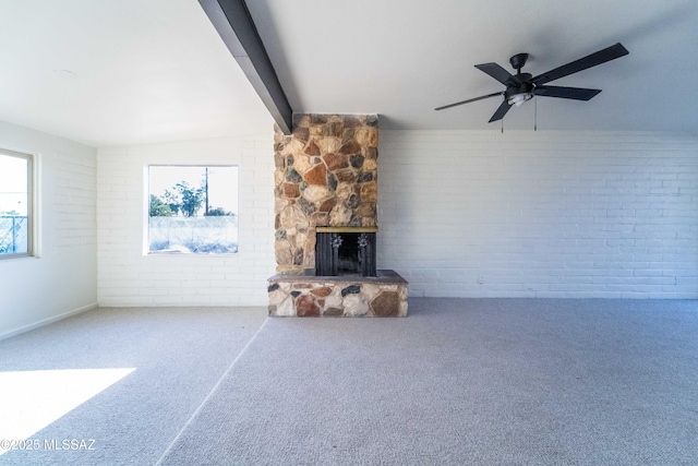 unfurnished living room with a fireplace, carpet floors, ceiling fan, and brick wall