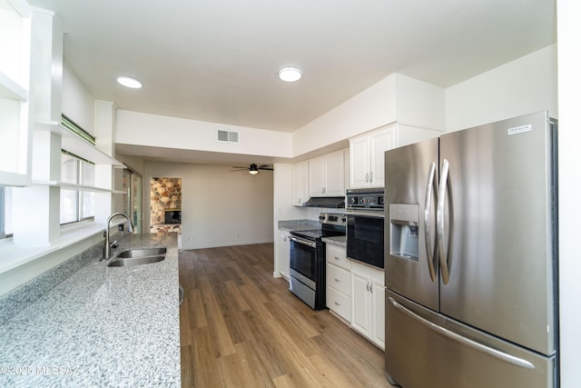 kitchen with sink, white cabinets, ceiling fan, stainless steel appliances, and light stone countertops