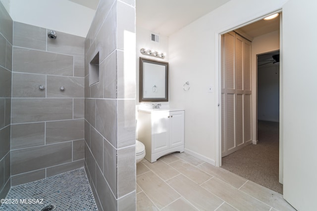 bathroom featuring tiled shower, vanity, and toilet