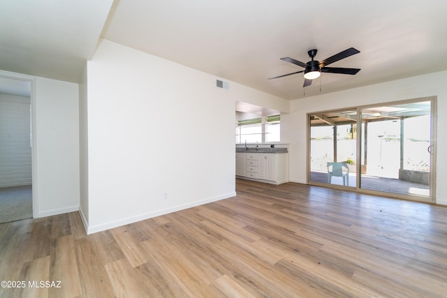 unfurnished living room featuring ceiling fan, sink, and light hardwood / wood-style flooring