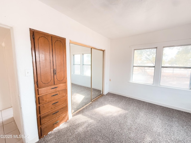 unfurnished bedroom with light carpet and a closet