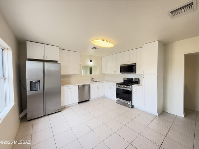 kitchen with white cabinets, light tile patterned floors, sink, and appliances with stainless steel finishes