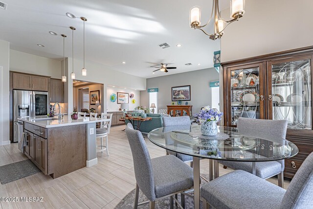 dining space with ceiling fan with notable chandelier and sink