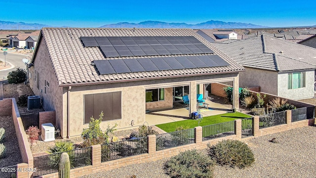 rear view of property with central air condition unit, a mountain view, solar panels, and a patio