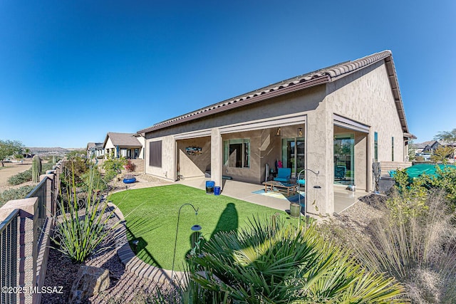 rear view of house featuring a lawn and a patio