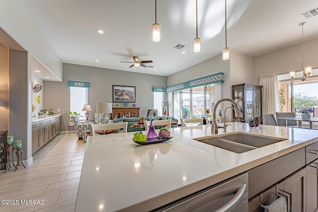 kitchen featuring decorative light fixtures, dishwasher, light stone countertops, ceiling fan with notable chandelier, and sink