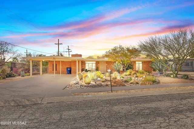 view of front of house featuring concrete driveway, brick siding, and an attached carport