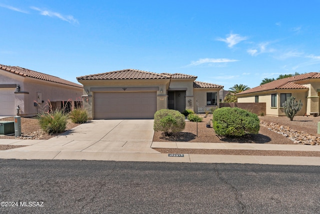 mediterranean / spanish-style house featuring driveway, a tiled roof, a garage, and stucco siding