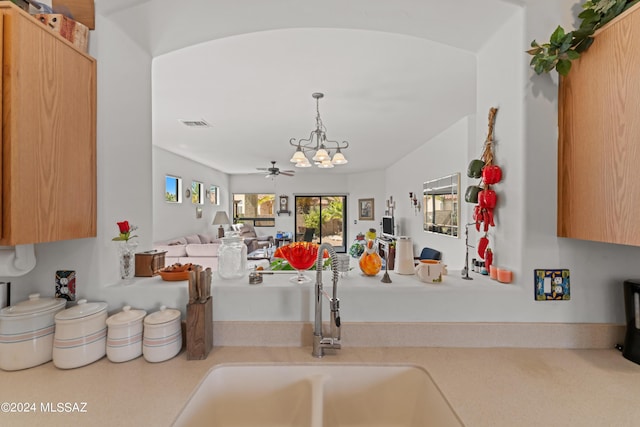 kitchen with visible vents, hanging light fixtures, light countertops, a sink, and ceiling fan with notable chandelier