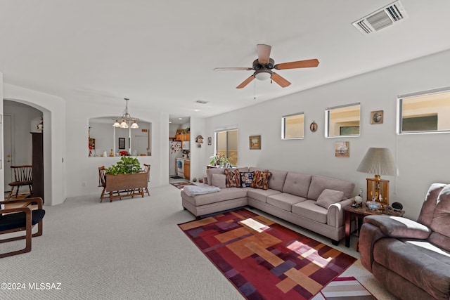 carpeted living area featuring arched walkways, visible vents, and ceiling fan with notable chandelier