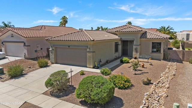 mediterranean / spanish-style house with stucco siding, concrete driveway, fence, a garage, and a tiled roof