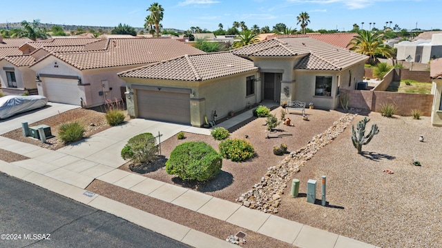 mediterranean / spanish-style house with a garage, a tile roof, fence, concrete driveway, and stucco siding