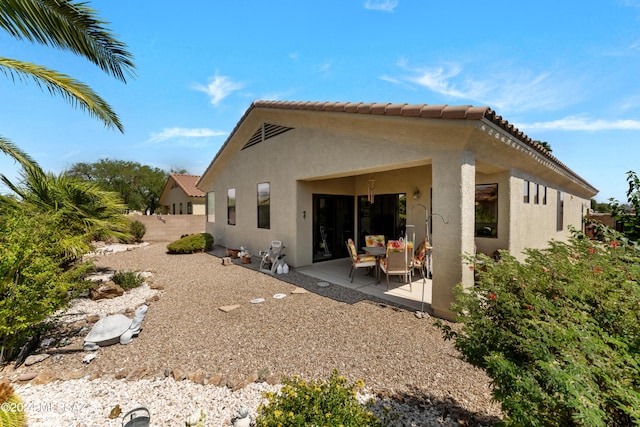 back of property featuring a tile roof, a patio, fence, and stucco siding