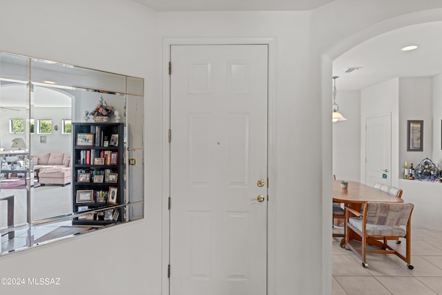 foyer entrance with light tile patterned floors, visible vents, and arched walkways