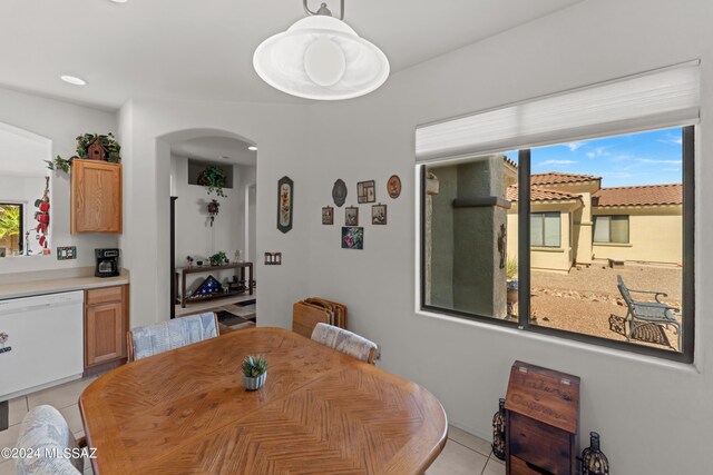 dining area featuring arched walkways, light tile patterned floors, and plenty of natural light