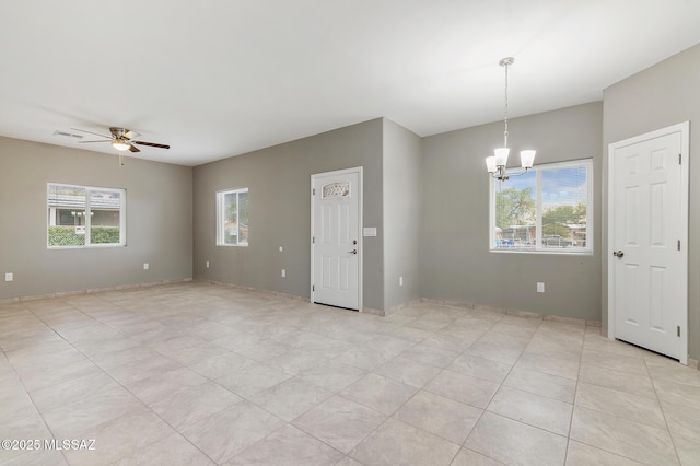 tiled empty room featuring ceiling fan with notable chandelier