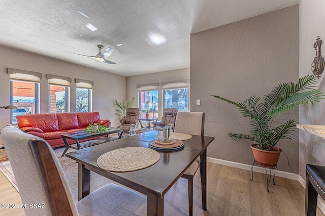 dining room with a textured ceiling, light wood-type flooring, and ceiling fan